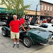 Belleville Oktoberfest festival goer poses in front of a dark green classic car.